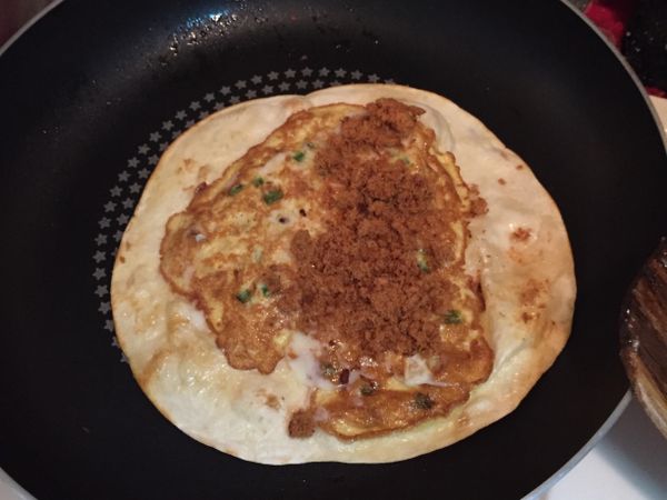 將烤餅翻面，蛋均勻熟透，擠上少許美乃滋，撒上少許肉鬆