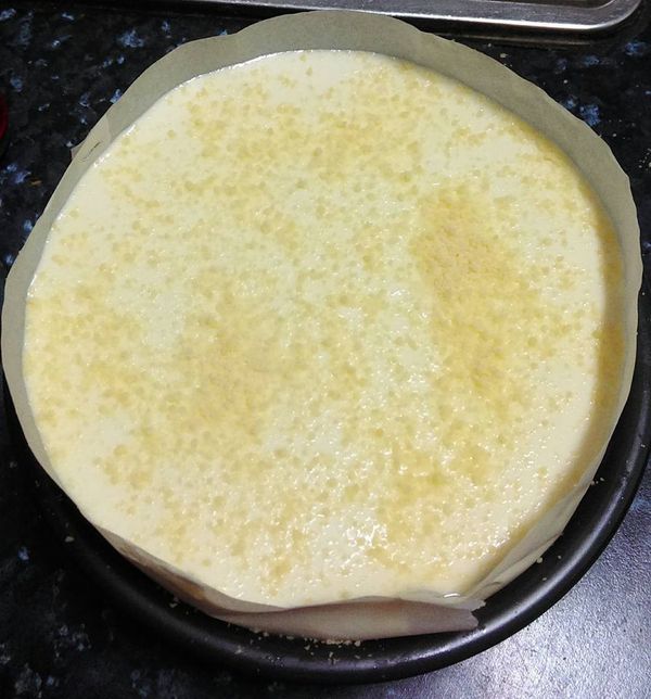 將蛋糕糊倒入麵糰已發至6-7分滿的土司模內,倒入後表面用刮刀稍抹平,灑乳酪粉