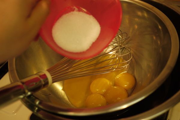 蛋黃與細砂糖放入攪拌盆，並隔水加熱攪拌至乳化。（蛋黃與砂糖不可以放在一起太久，要馬上攪拌，也請勿持續加熱，不然蛋黃會結塊，乳化的蛋黃糊顏色會變淡且黏稠）