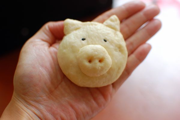 接著捏一個小麵團當鼻子，牙籤戳洞當鼻孔，再捏兩個小三角形麵團當耳朵，最後黏上黑芝麻當眼睛，就是可愛的小豬！