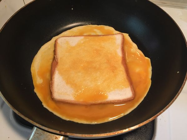 熱鍋完成後蛋液先下2/3，然後把壓扁的吐司放上去，在把剩下1/3的蛋液倒在吐司上，用鍋鏟稍微抹均勻。
