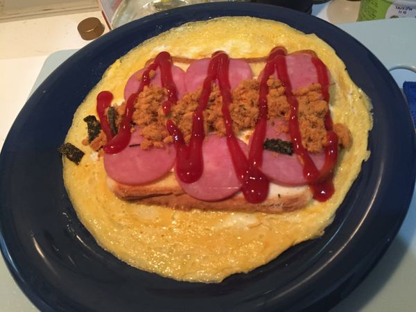 1. 趁蛋皮上的吐司還是熱的時候，將起司片鋪上。
2. 依喜好鋪上火腿、肉鬆，最後再擠一些蕃茄醬調味。