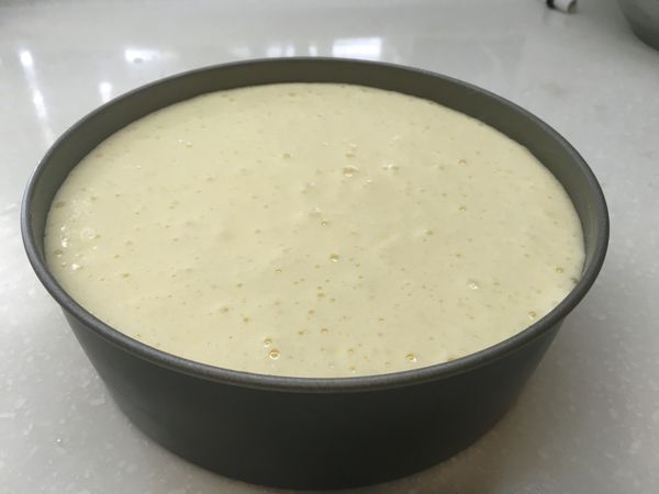 先將蛋糕模塗上奶油以利烤後脫模，將蛋糕液倒入8吋的蛋糕模中，輕敲桌面將空面震出。