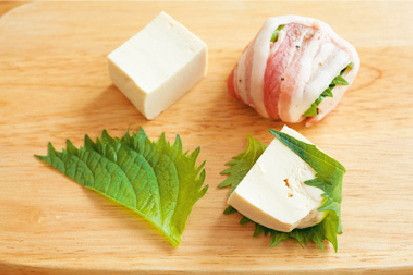 每片豆腐分別用一片紫蘇葉包起來，再用一片已經灑上胡椒的豬肉片包捲起來。