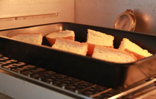 將麵包切片抹上奶油烤熱。