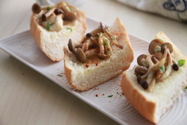 將炒好菇道鴻喜菇放在麵包上，灑上新鮮巴西利葉碎與辣椒粉即完成。