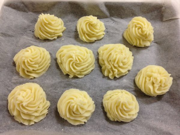 把拌勻的馬鈴薯泥放入擠花袋，擠成自己喜歡的大小形狀後，表層塗抹剩下的1/3奶油後入烤箱烘烤。