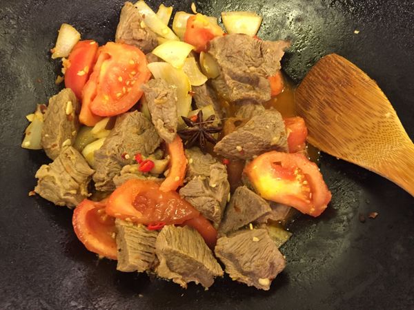 油入鍋燒熱，蕃茄和洋蔥下鍋炒香，再下牛肉和爆香材料同炒。