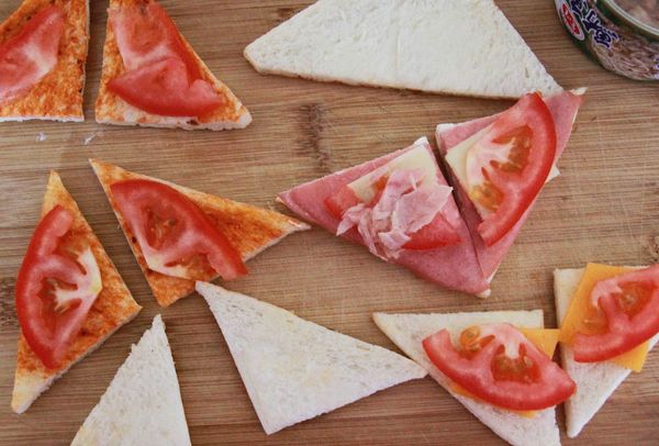 將起司三重奏三明治拆開後取下起司片與火腿片後對切成一口大小。再將每一片三明治土司片上放上三明治中的起司片、火腿片。