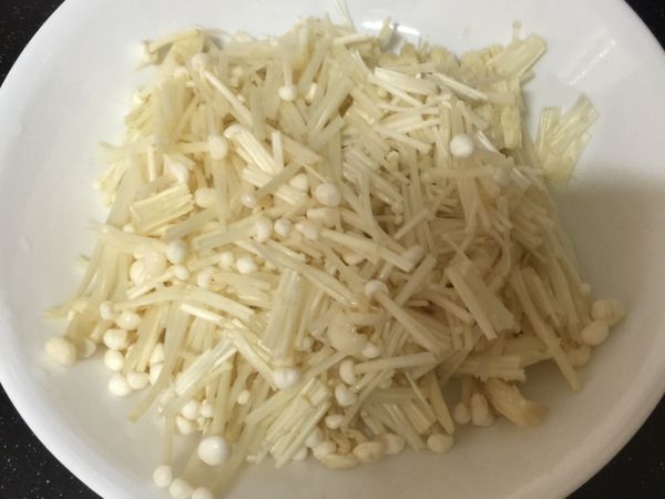 將金針菇一半切碎一半不切鋪平在盤子裡。