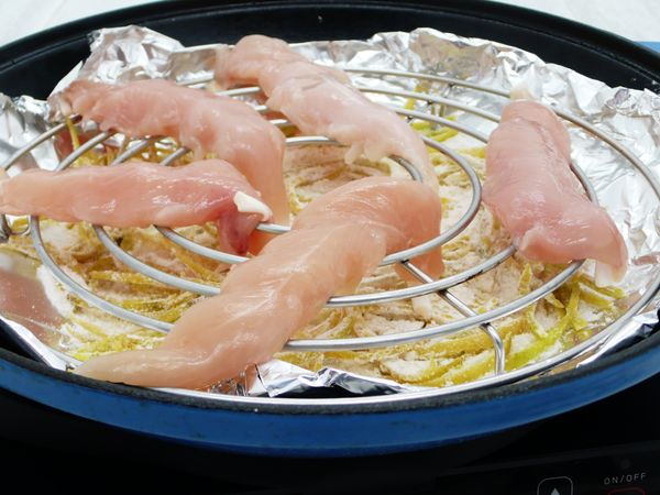 再將不銹鋼烤架放上，接下來把雞里肌平均的擺置烤架網上