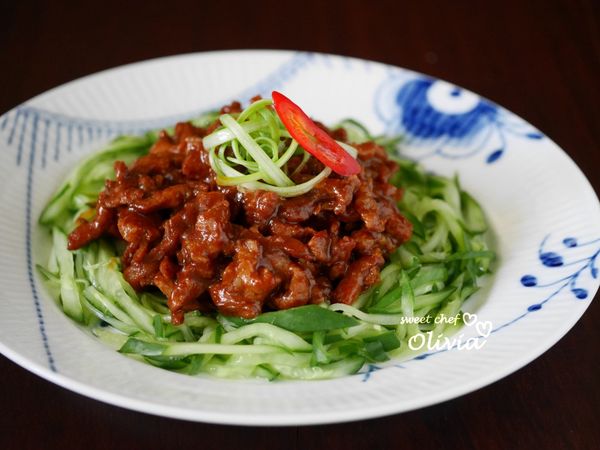 盤底鋪上蔥絲，周圍繞著小黃瓜絲，盛上京醬肉絲即可。