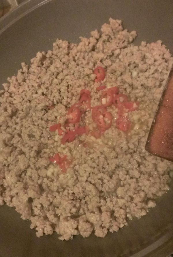 鍋中加油後先將大蒜及紅辣椒略炒，再把絞肉倒入鍋中繼續炒散。