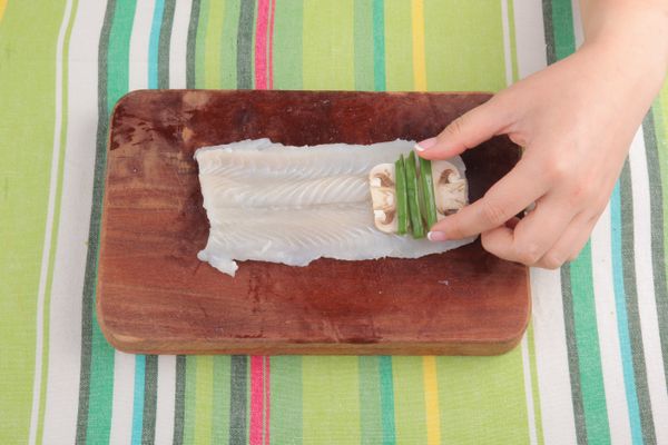 鯰魚柳鋪上蘑菇絲及葱段，灑上適量的黑胡椒及鹽後捲起，用葱綁好。煮滾清水後，加入惹味粉拌勻，滾起後成汁料，備用。