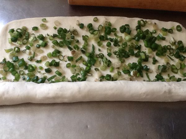 9.灑上蔥花，由一側往內捲，捲成長圓柱狀，將蔥花包覆在內。