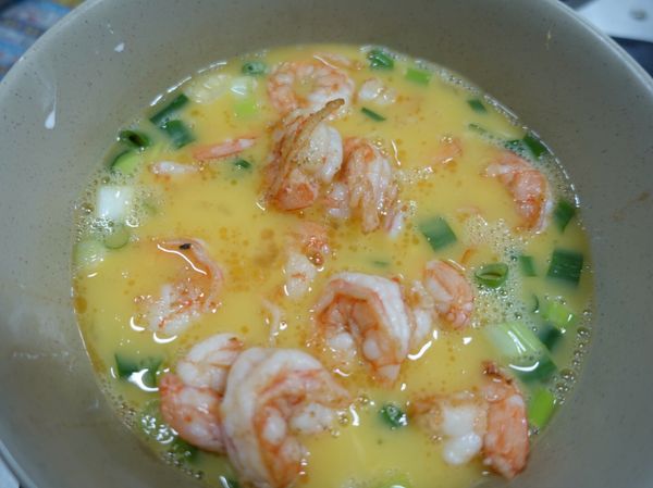 將蛋打入碗內，加少許鹽跟微量的糖.蔥花.太白粉水，打均勻後，放入蝦仁