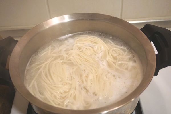 起一鍋熱水，加入兩人份拉麵條，熟煮撈起，接著燙青菜