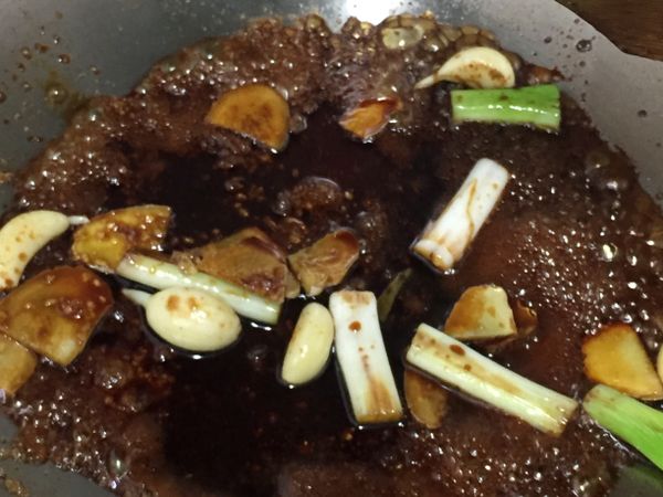 熱鍋，加入少量油，炒香蔥白、薑片、蒜頭後，續加入冰糖和醬油炒香後，加入水適量