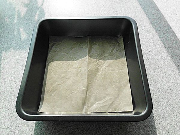將拌好的麵糊倒入墊了防沾紙的烤模中抹平“敲一敲”(雖使用不沾的模型,但建議還是鋪張防沾紙較容易取出。)

分量若減半,用耐熱的方形或長方形保鮮盒~或是磅蛋糕用的長條烤模 也可以。