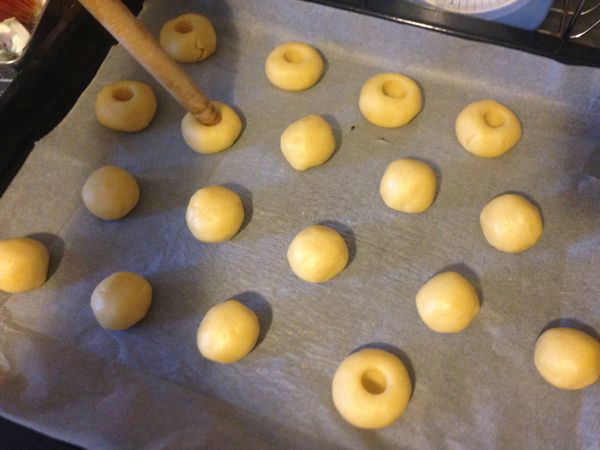 這個麵團可以做18個到20個，看自己喜歡，我不一定，今天做了18個，還可以更小，我這個已經差不多了。把小麵團揉圓，放在有烤盤紙上如圖，中間用桿麵棍戳一個洞，不要戳得太深，有個凹洞就好了，太深可能會露餡。