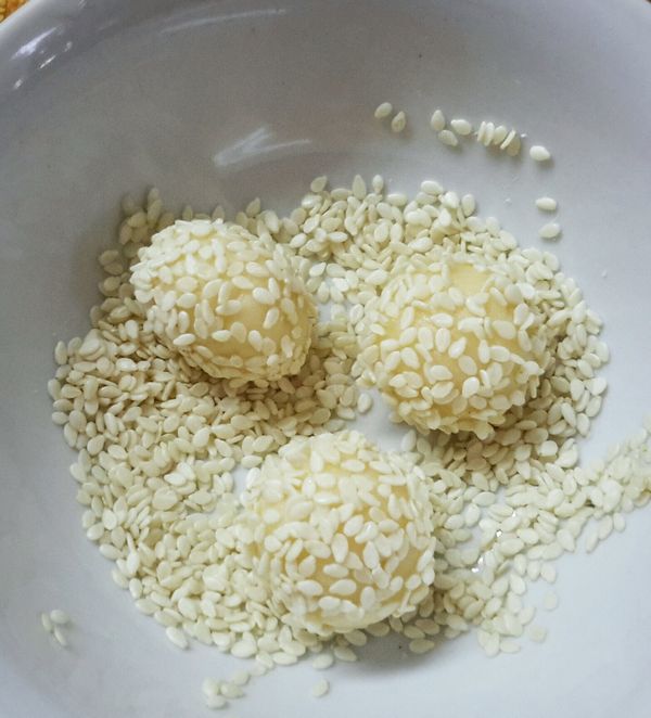 在麵糰表面沾少許水，再沾滿芝麻，用雙手搓揉一下