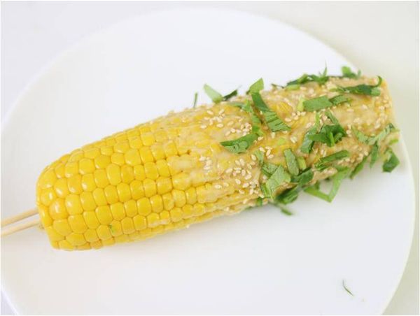 黃金玉米棒塗上奶油芝麻油混合物，撒上白芝麻及芫荽碎。