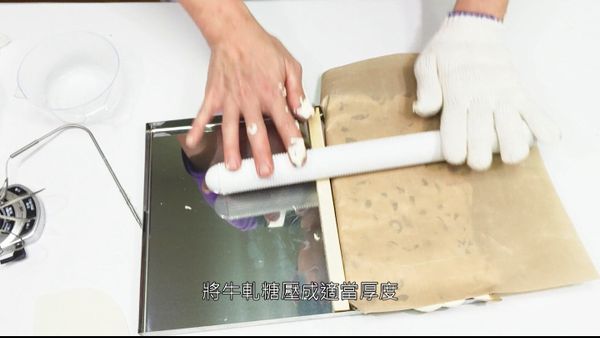用擀麵棍將牛軋糖壓至貼合糖盤，待冷後方可切割
