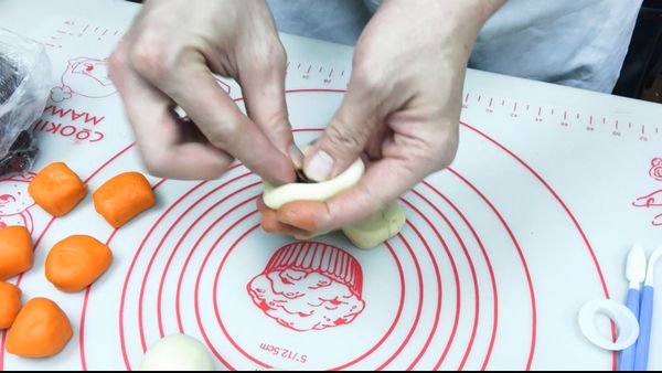 取一小白色麵糰壓扁，裡面包入蔓越乾或喜歡的餡料