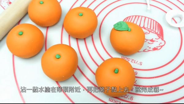 沾一點水在橘子上，將葉子黏上去