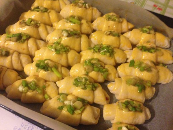 烤盤上放烤盤紙，把做好的麵包卷依序斜放在烤盤上，依次做好放好等待二次發酵，麵包卷會再次膨脹一些，此時刷上蛋汁，然後用乾淨的剪刀，在麵包卷的上面剪一個洞，洞裡放入適量的蔥花胡椒餡如圖。就可送入預熱好的烤箱，200度，中下層，大約20到25分鐘左右，直到表面金黃即可。