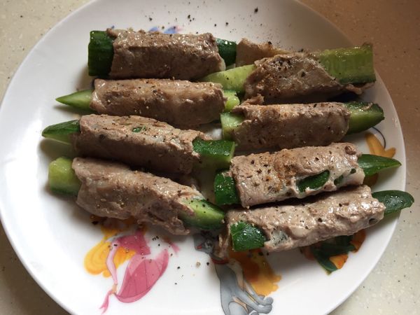 將小黃瓜對半切再對半切，再將小黃瓜橫著切一半（由長條切短），再將肉片切一半鋪平（看你肉片的大小），再將小黃瓜捲起，收口朝下入平底鍋煎熟，裝盤撒上調味料，完成！