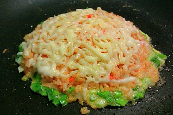 將乳酪絲鋪在茄汁洋蔥鮪魚飯上。