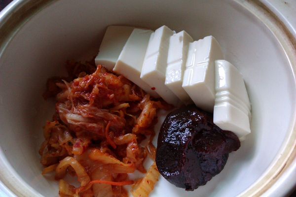 鍋內放入炒過的泡菜絲跟韓式辣椒醬跟切片的豆腐，加水至淹過食材