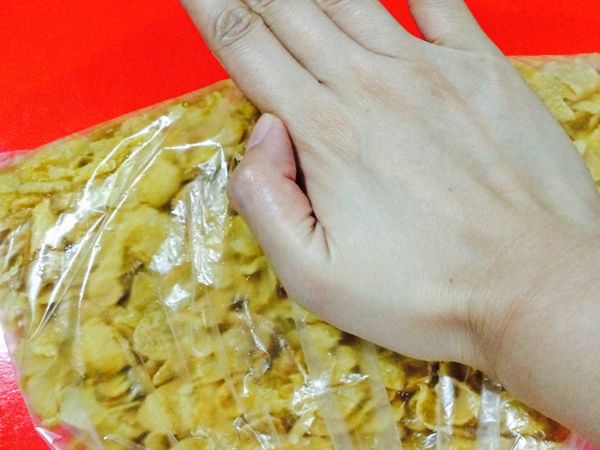 首先將生杏仁片放入烤箱以160度烤8-10分鐘，把玉米片放入塑膠袋袋中軽軽稍微壓碎一點，這樣做出來的巧克力酥片比較有不同口感