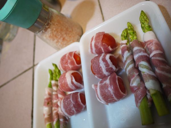 將其中3片豬五花薄片切半後，捲起小蕃茄（6顆）。再用剩下6片豬五花一一將蘆筍（6隻）捲妥。