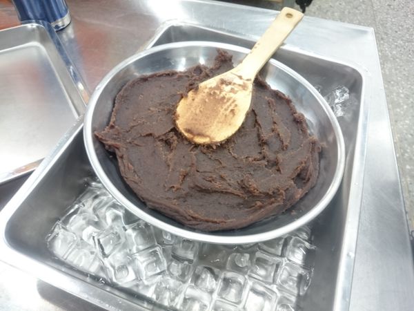 將豆沙團放入鐵盤中，並在旁用冰塊使其放涼，放涼後分成16份，滾圓備用