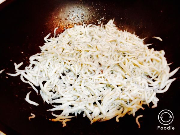 吻仔魚入熱鍋乾炒，稍微炒去表面水分後加入約30cc橄欖油；先第一次以柴魚粉淡淡調味。