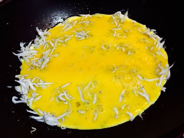 倒入6粒打散的土雞蛋，中小火烘煎1分鐘後蓋上鍋蓋燜5分鐘。蛋液加入約1茶匙白胡椒粉與1.5-2茶匙的柴魚粉、10cc無鹽米酒。