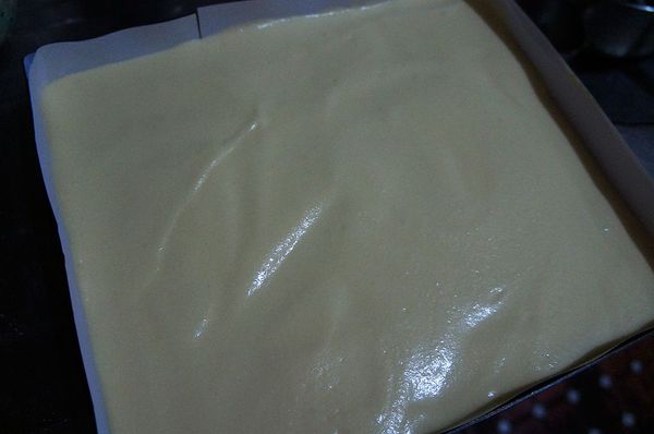 將1/3蛋白霜加入蛋黃糊中以刮刀用拌切方式輕輕混和均勻，再倒入剩餘蛋白霜鍋中攪拌均勻後倒入已鋪好白報紙模中，入已預熱至175度烤箱烤18~20分鐘。