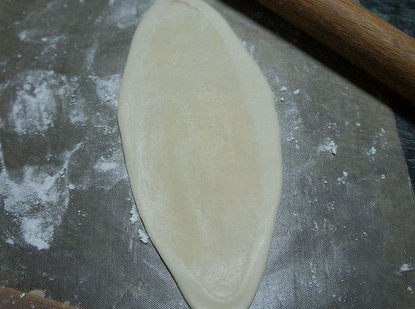 取一包好的水油皮油酥團按壓撖成長形麵皮由上往下捲起。