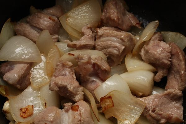 熱油鍋，依序爆香洋蔥、蒜頭、梅花肉塊直到焦香。