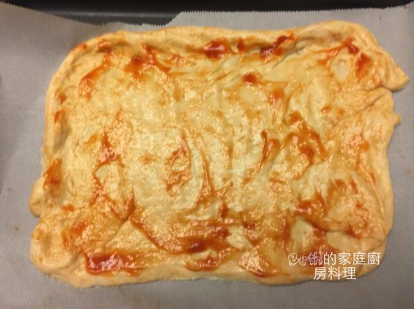 將麵糰分成2份，用手壓平成圓形或方形，邊邊稍微捏厚ㄧ點，鋪在放有烘培紙的烤盤上，表面塗上蕃茄醬