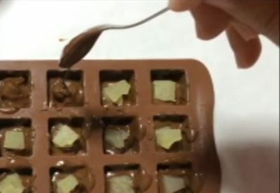 軟塑膠製冰盒裡、先倒進1/3巧克力醬、放進擦乾水份的蜜糖蘋果、再將剩餘的巧克力醬全部舗上。