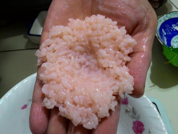 將蒸熟的道明寺粉分成8份。
此時準備一盆冷水，雙手沾水，趁熱將米糰壓平，中間內凹，放入紅豆餡