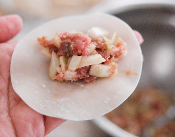 放餡料在餃子皮中央，用手指將皮邊塗水，對疊