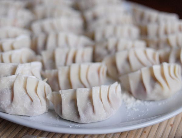 包好的餃子放在灑有麵粉的碟上