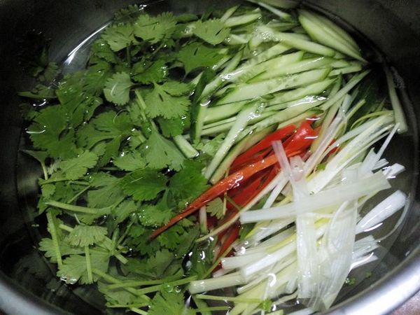 小黃瓜切絲；蔥只取蔥白部位切絲；紅辣椒去籽切絲；芫荽切小段；全部泡在冰鹽水中冰鎮3分鐘，然後撈起瀝乾備用。