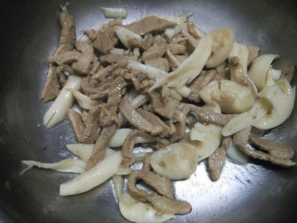 鍋中油熱了時，將肉絲先下鍋炒。炒至半熟時，將白精靈菇放入，炒至全熟，盛到調理盆。