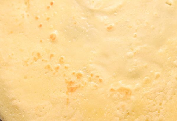 用廚房紙巾沾取少許無鹽奶油塗抹均勻在鍋面後(薄薄一層即可)，先以中火熱鍋，接著將適量粉糊倒入鍋中並搖晃均勻成圓形薄片，等到餅皮表面固化且能夠輕易被移動時，將餅皮翻面，並煎熟至兩面均勻上色如圖。