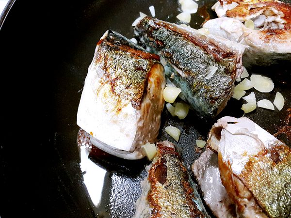 起油鍋將鯖魚煎至兩面金黃後放入蒜末一起爆香